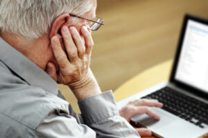 elderly man looking at laptop